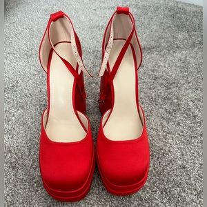 Satin red platform heel with ankle strap.